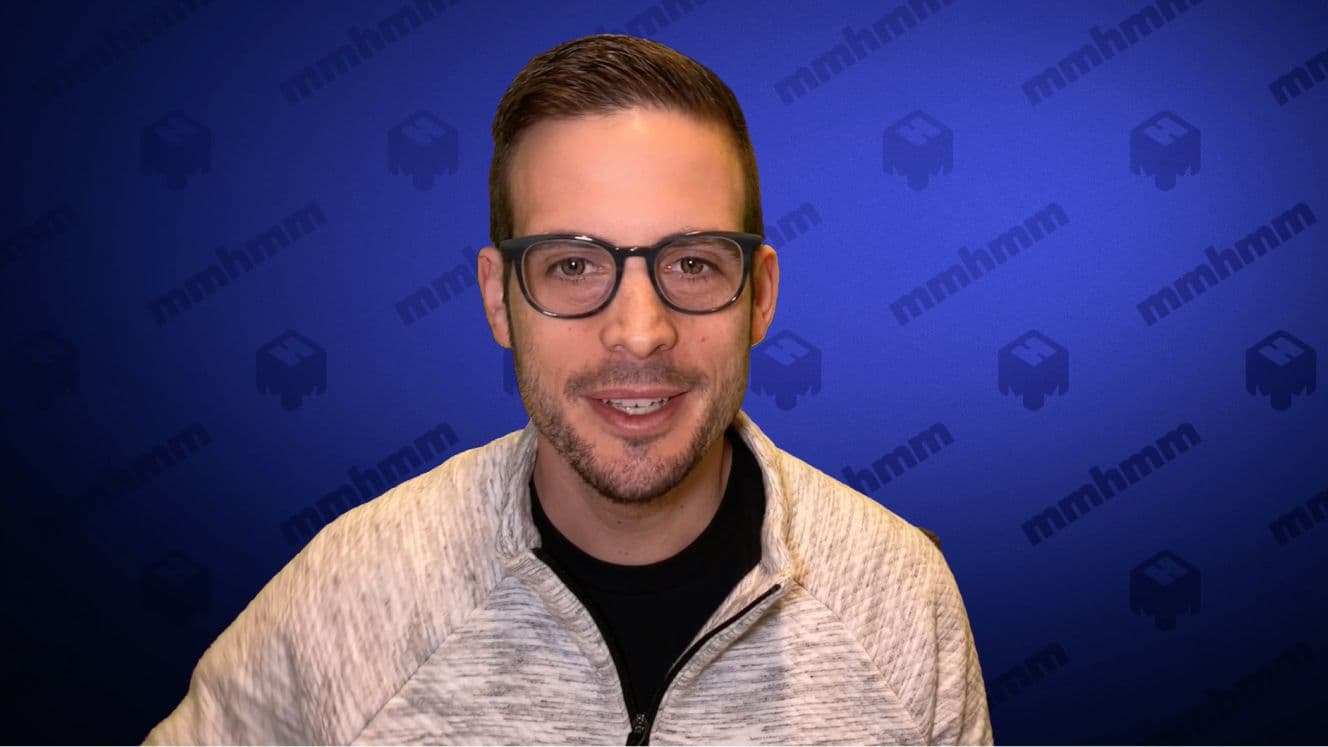 Man with glasses and dark hair in front of a blue background that says mmhmm