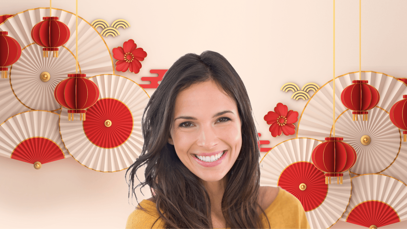 Person with long brown hair standing in front of red and white paper fans and lanterns